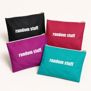 May include: Four rectangular zippered pouches in black, magenta, dark pink, and teal. Each pouch features the text "random stuff" printed in white letters on the front. The pouches have gold-toned metal zippers along the top edge.
