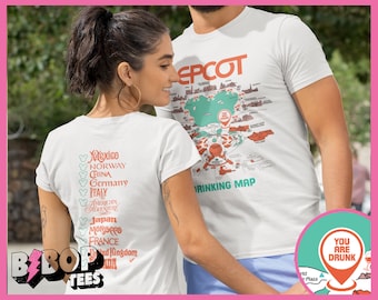Könnte beinhalten: Ein Paar trägt weiße T-Shirts mit einer Karte des Epcot World Showcase und einer Liste der vertretenen Länder. Das T-Shirt des Mannes lautet "EPCOT Drinking Map" und das T-Shirt der Frau listet die Länder des World Showcase auf. Das Bild enthält auch ein rotes und weißes Schild mit der Aufschrift "You Are Drunk" mit einem Weinglas-Symbol.