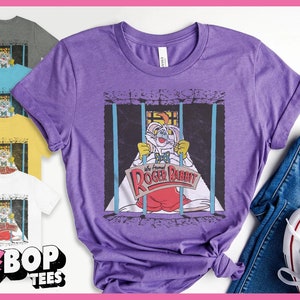 K&ouml;nnte beinhalten: Lilafarbenes T-Shirt mit einem Aufdruck von Roger Rabbit in einer Gef&auml;ngniszelle. Der Text auf dem Aufdruck lautet "We framed Roger Rabbit".