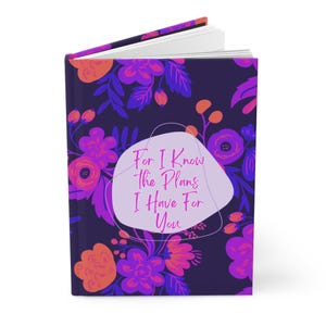 Könnte beinhalten: Ein violettes Notizbuch mit einem Blumenmuster und dem Text "For I Know The Plans I Have For You" in Rosa.
