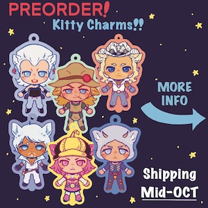 May include: Six illustrated acrylic charms featuring chibi-style characters with cat ears, arranged on a dark purple background with yellow stars. Text reads PREORDER! Kitty Charms!! and MORE INFO with an arrow pointing to the right.