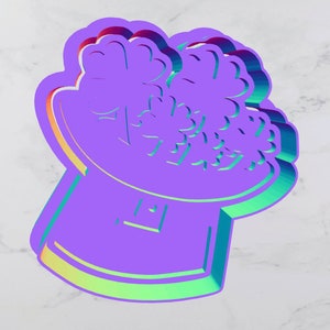 May include: A purple 3D printed cookie cutter shaped like a bouquet of shamrocks in a pot. The cookie cutter has a shiny, iridescent finish.