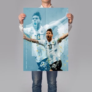 May include: A blue and white watercolor-style poster featuring a soccer player in a white jersey with the number 10 on it. The player is celebrating a goal with his arms raised in the air. The poster has the text "Lionel Messi / World Cup 2022" at the bottom.
