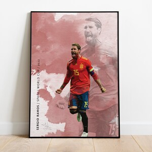 May include: A digital illustration of a soccer player in a red and blue uniform with the number 15 on the front. The player is celebrating a goal with his arms raised. The background is a watercolor-style image of the Spanish flag. The text "SERGIO RAMOS / SPAIN / WORLD CUP / 2022" is on the left side of the image.