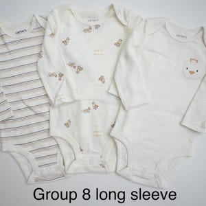 May include: Three long-sleeve Carter's bodysuits. One features horizontal stripes in brown and blue. Another has a repeating pattern of small ducks. The third is solid cream with a small duck graphic on a chest pocket. Text reads: Group 8 long sleeve.