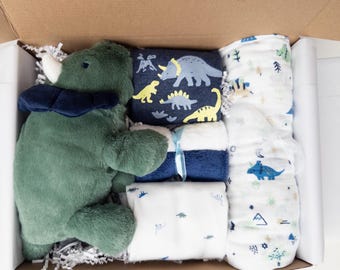 Set de regalo para bebé con temática de dinosaurios: body, manta para envolver y peluche.