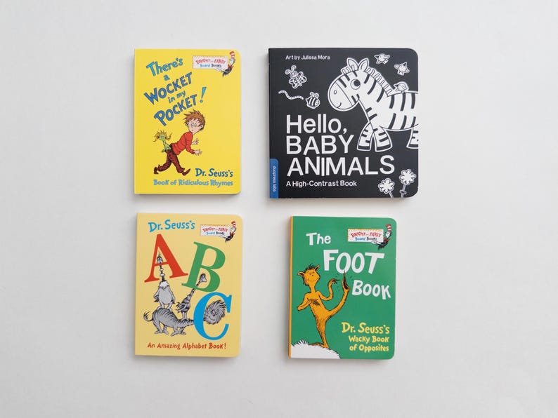 May include: Four board books arranged in a grid. Top left: yellow cover, There's a Wocket in my Pocket! Top right: black cover, Hello, Baby Animals. Bottom left: yellow cover, Dr. Seuss's ABC. Bottom right: green cover, The Foot Book.