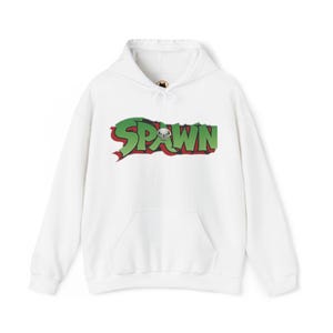 May include: A white long-sleeve hooded sweatshirt featuring a front kangaroo pocket and a drawstring hood. The centre of the chest displays the word SPAWN in large green letters with a stylised skull icon replacing the letter A, outlined in red.