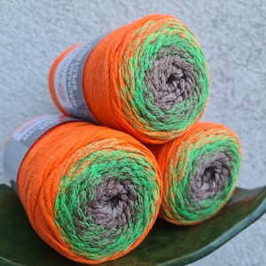 Puede incluir: Tres ovillos de cord&oacute;n de macram&eacute; naranja, verde y marr&oacute;n. El cord&oacute;n est&aacute; trenzado y tiene un aspecto moteado.