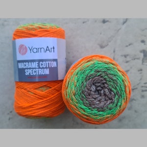 Puede incluir: Dos ovillos de hilo de algod&oacute;n para macram&eacute; de color naranja, verde y marr&oacute;n. El hilo est&aacute; etiquetado como "YarnArt Macrame Cotton Spectrum".