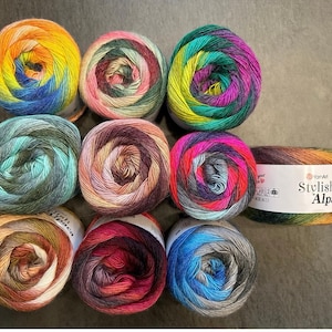 May include: Ten skeins of yarn in various color combinations, including blue, green, orange, red, and brown. The yarn is labeled "Stylish Alpaca" by YarnArt.