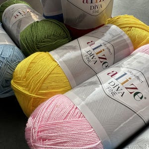 Puede incluir: Primer plano de seis ovillos de hilo en varios colores, incluyendo azul, verde, amarillo y rosa. Cada ovillo tiene una etiqueta que dice "Alize Diva Fine Silky Effect".