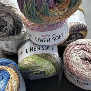 Puede incluir: Cinco ovillos de hilo YarnArt Linen Soft en varias combinaciones de colores. El hilo es una mezcla de lino y algod&oacute;n, y es suave y liso al tacto. Los ovillos est&aacute;n etiquetados con el nombre de la marca y el nombre del hilo.