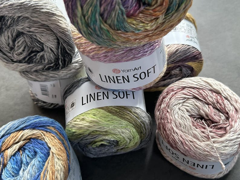 Puede incluir: Cinco ovillos de hilo YarnArt Linen Soft en varias combinaciones de colores. El hilo es una mezcla de lino y algod&oacute;n, y es suave y liso al tacto. Los ovillos est&aacute;n etiquetados con el nombre de la marca y el nombre del hilo.