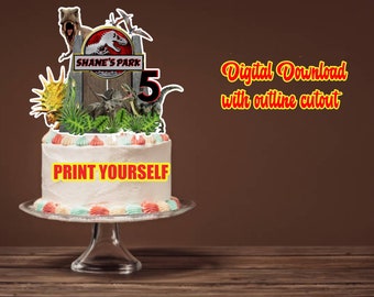 May include: A dinosaur-themed cake topper featuring a gate with the text SHANE'S PARK, a large number 5, and various dinosaur illustrations including a T-Rex, triceratops, and raptor, displayed on a white frosted cake with colourful piping.