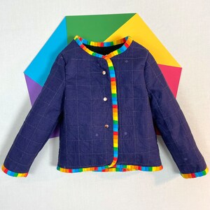 May include: A navy blue quilted jacket with a rainbow trim around the collar, cuffs, and hem. The jacket has a button closure and a black lining.