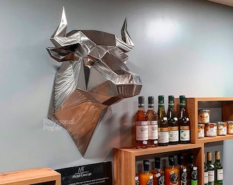 May include: A silver metal bull head sculpture with a geometric design, mounted on a wall. The sculpture is displayed above a wooden shelf with bottles of wine and jars of preserves.