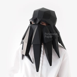 Könnte beinhalten: Eine Person trägt eine schwarze Papiermaske, die einem Oktopus ähnelt. Die Maske besteht aus gefaltetem Papier und hat ein geometrisches Design. Der Text "Polygonal Paper" ist auf der Maske sichtbar.