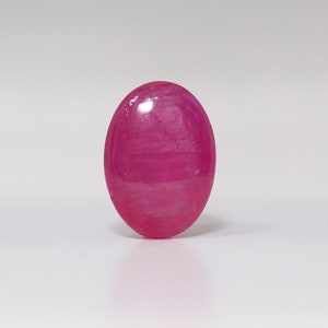 Puede incluir: Una gema ovalada de color rosa vibrante con una superficie lisa y pulida.