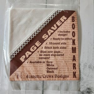 May include: A beige Page Saver bookmark with a white lace trim. The brown label reads "Page Saver Bookmark" and includes text about the product's features and the brand "Jeanette Crews Designs."