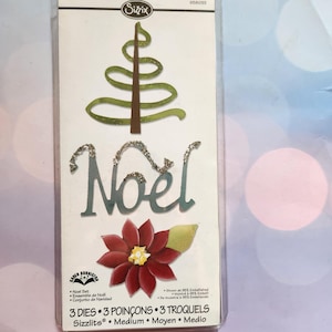 May include: A Sizzix Noel set in a clear plastic package. The set includes a glittery green Christmas tree, the word "Noel" in silver glitter, and a red poinsettia die cut. The package also includes the text "3 Dies 3 Poinçons 3 Troquels".