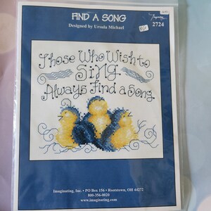 May include: Cross-stitch kit titled "Find a Song" with a blue border. The design features the text "Those Who Wish to Sing Always Find a Song" above a group of yellow and blue birds. Designed by Ursula Michael.