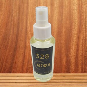 Peut inclure: Un flacon en verre transparent avec une buse de pulvérisation blanche et une étiquette noire. L'étiquette indique "La Parfumerie Qiwa Family" et "328 Qiwa".
