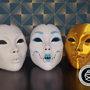 Puede incluir: Tres máscaras decorativas, una blanca con detalles azules, una blanca con detalles azules y rosas, y una dorada. Las máscaras son todas en el estilo de un rostro humano con rasgos exagerados. La máscara dorada tiene el texto "AUTHORIZED SELLER" impreso en la parte inferior.