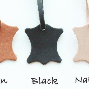 May include: Three leather swatches in tan, black, and natural colors. Each swatch is attached to a leather strap.
