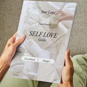 Könnte beinhalten: Ein weißes und graues Selbstliebe-Arbeitsbuch mit dem Titel "SELF LOVE Guide" und dem Text "A4 workbook | 10 pages". Das Arbeitsbuch ist auf Seite 1 geöffnet und wird von den Händen einer Person gehalten.
