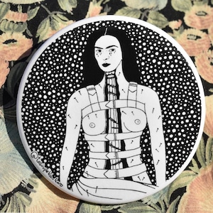 May include: Black and white illustration of a person with a distressed, stitched-up body. The background is a black and white polka dot pattern.