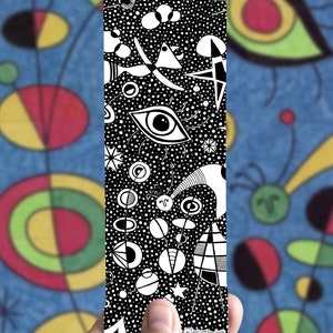 May include: Black and white bookmark with a whimsical design featuring a large eye, circles, stars, and other abstract shapes. The bookmark is printed with the text "@tasirupekaharo".