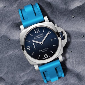 May include: A blue rubber watch band with a silver watch face. The watch face has black hands and markers, and the words "Luminor Marina" and "Panerai eSteel" are printed on it.