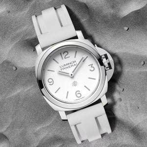 May include: A white wristwatch with a white rubber band. The watch face is white with black markings and the text "Luminor Panerai" printed on it.