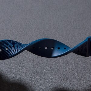 May include: A dark blue watch strap with a textured surface and multiple holes for adjusting the fit.