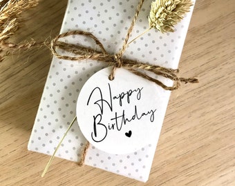 May include: A white gift box with gray polka dots wrapped with twine and a white gift tag that says "Happy Birthday" with a small heart.