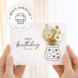 May include: A white birthday card with a hand-drawn illustration of a vase filled with daisies and dried flowers. The card reads "Happy Birthday to You" in elegant script. A digital download icon is in the upper left corner.