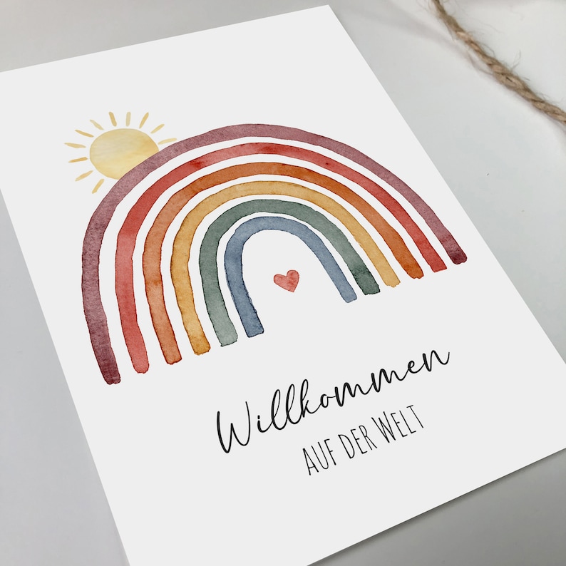 Postkarte mit Motiv: Regenbogen mit aufgehender Sonne. Darunter der Text: Willkommen auf der Welt