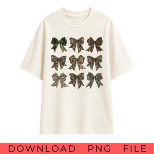 May include: A cream-colored short-sleeve t-shirt featuring a graphic print of nine bows arranged in a three-by-three grid. Each bow displays a different pattern, including various shades of green, brown, and tan camouflage and leopard print designs.