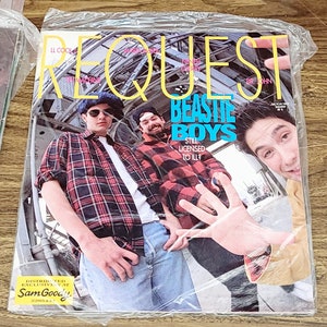 May include: A magazine cover featuring a photo of three men, with the title "REQUEST" and the words "BEASTIE BOYS STILL LICENSED TO ILL?" in large, bold letters. The magazine is distributed exclusively at Sam Goody.
