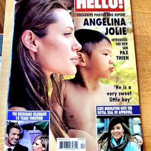 May include: A magazine cover featuring Angelina Jolie holding her son Pax Thien. The cover headline reads "Angelina Jolie Introduces Her New Son Pax Thien". The magazine is titled "Hello!" and the date is March 27, 2007.