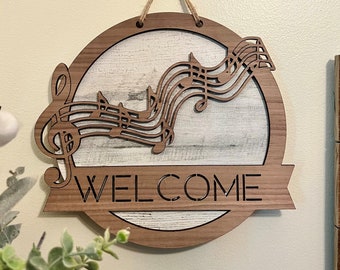 May include: A wooden welcome sign with a whitewashed background and a music note design. The sign is hanging from a rope and says "WELCOME" in a banner below the music notes.