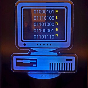 May include: A blue and white computer-shaped night light with the word "Ethan" spelled out in binary code on the screen.
