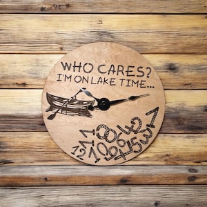 May include: A wooden clock with a black hand and a rope design around the numbers. The clock face says "Who cares? I'm on lake time..." and has a small image of a boat with oars.