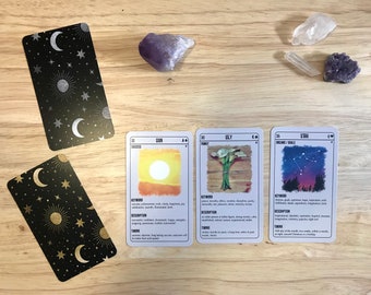 May include: Tarot cards with celestial designs and illustrations of the sun, lilies, and a starry night sky. The cards are on a wooden surface with crystals.