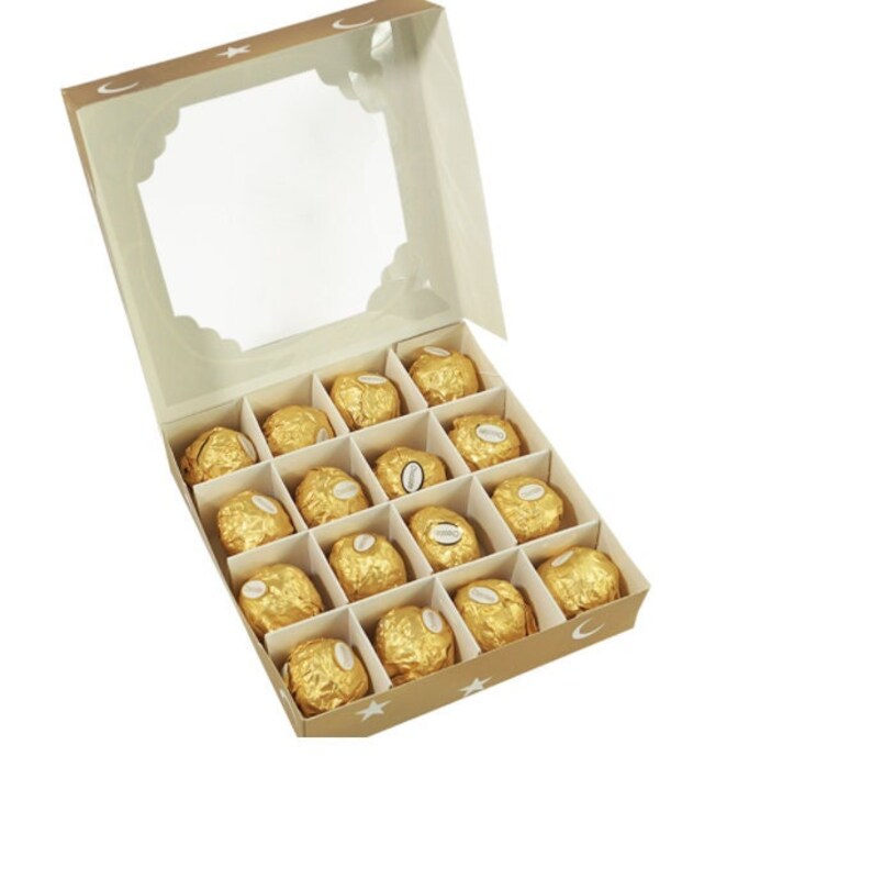 May include: A box of chocolates with a clear lid. The box is decorated with a crescent moon and stars. The chocolates are wrapped in gold foil.