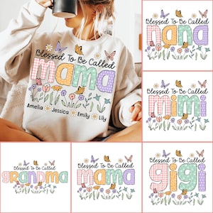 Puede incluir: Una sudadera blanca con un dise&ntilde;o floral y el texto "Blessed To Be Called mama" en letras de colores de patchwork. Los nombres Amelia, Jessica, Emily y Lily est&aacute;n escritos debajo del texto principal.