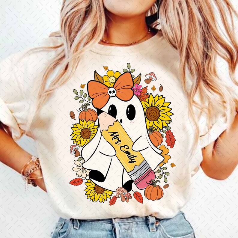 May include: A white ghost with a black skull and orange bow holding a yellow pencil with the text "Mrs. Emily" on it. The ghost is surrounded by sunflowers, pumpkins, and fall leaves.