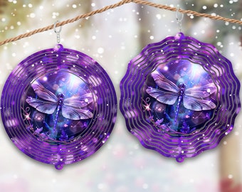May include: Purple metal wind spinner with a dragonfly design. The dragonfly has a purple and blue body with clear wings. The background is a swirling galaxy pattern with stars and sparkles.