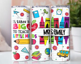 May include: A white tumbler with a school-themed design. It features colorful illustrations of school supplies, including crayons, a pencil, and a school bus. The text reads "It takes a BIG heart to teach LITTLE MINDS" and "MRS. EMILY".